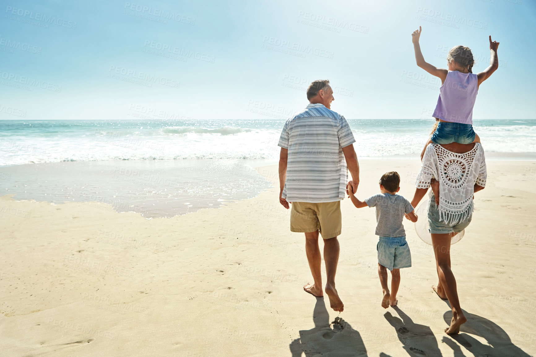 Buy stock photo Parents, children and beach or happy summer travel sea vacation, ocean sunshine or siblings.. Man, woman and kid piggy back or behind on sand for family holiday walk or outdoor, clean air or relax