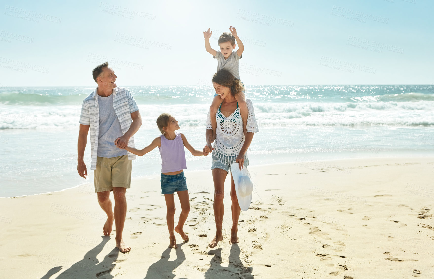 Buy stock photo Happy family, walking and holding hands at beach in summer for relax, travel and holiday in Miami. Parents, children and people at ocean with love for vacation, trust and shoulder ride by water