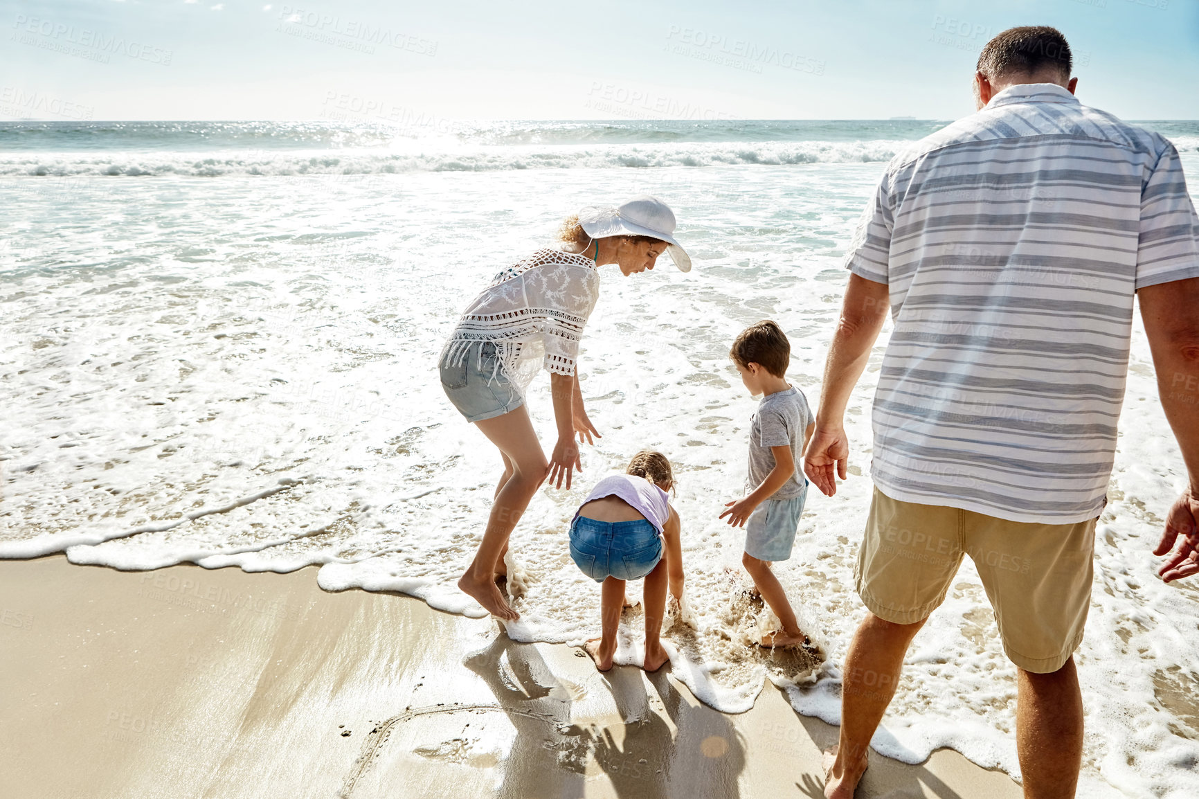 Buy stock photo Happy family, water and playing at beach in summer for relax, travel and holiday in Miami. Parents, children and people at ocean with back view for vacation, trust and bonding together by sand