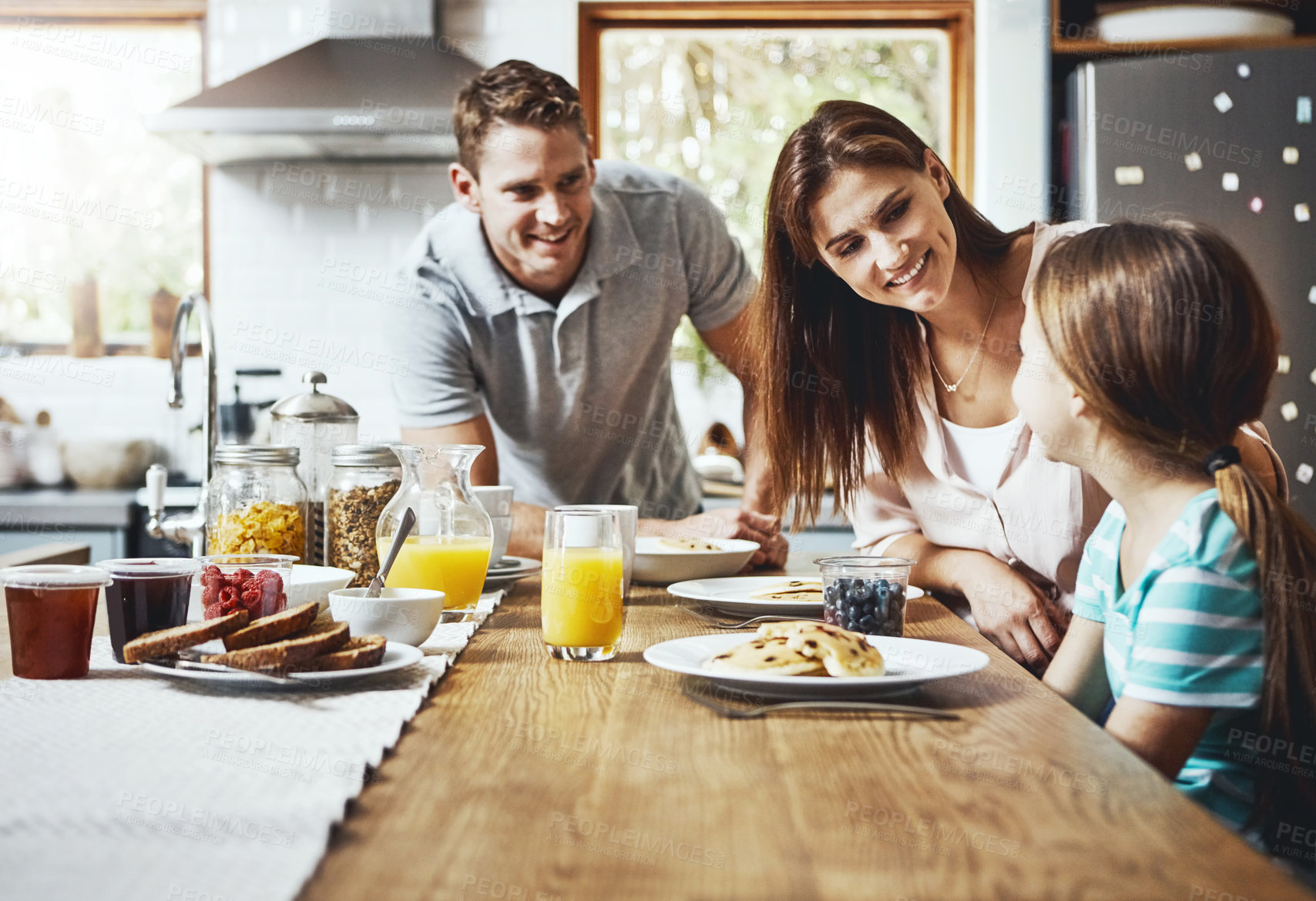 Buy stock photo Family, breakfast and kid with smile in morning for healthy diet, growth and child development. Happy, father and mother with little girl with food on weekend for nutrition, support and care at home