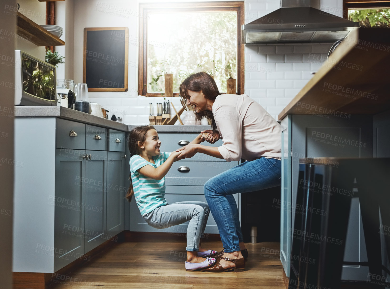 Buy stock photo Shot of a mother playing with her little daughter in the kitchen at home