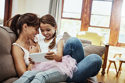 Buy stock photo Shot of a little girl using a cellphone while bonding with her mother at home