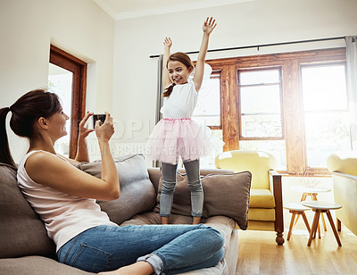 Buy stock photo Shot of a mother taking a photo of her little daughter having fun at home