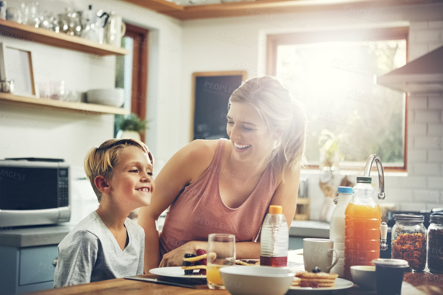 Buy stock photo Shot of a woman sitting with her son while he's having breakfast