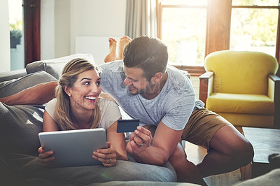 Buy stock photo Shot of a young couple doing some online shopping on a digital tablet