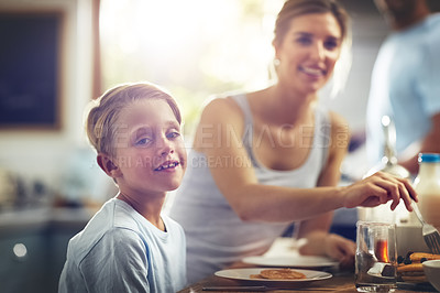 Buy stock photo Cropped shot of a little boy having breakfast with his mom sitting in the background