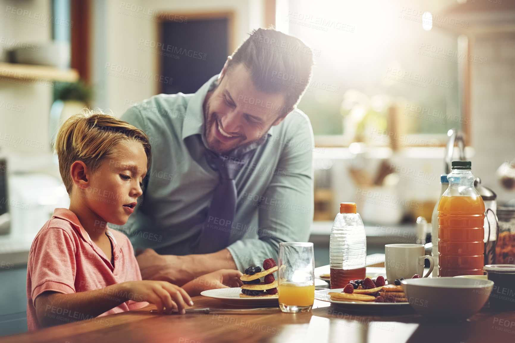 Buy stock photo Shot of a man sitting with his son while he's having breakfast