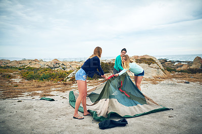 Buy stock photo Shot of a group of female friends setting up a tent outdoors
