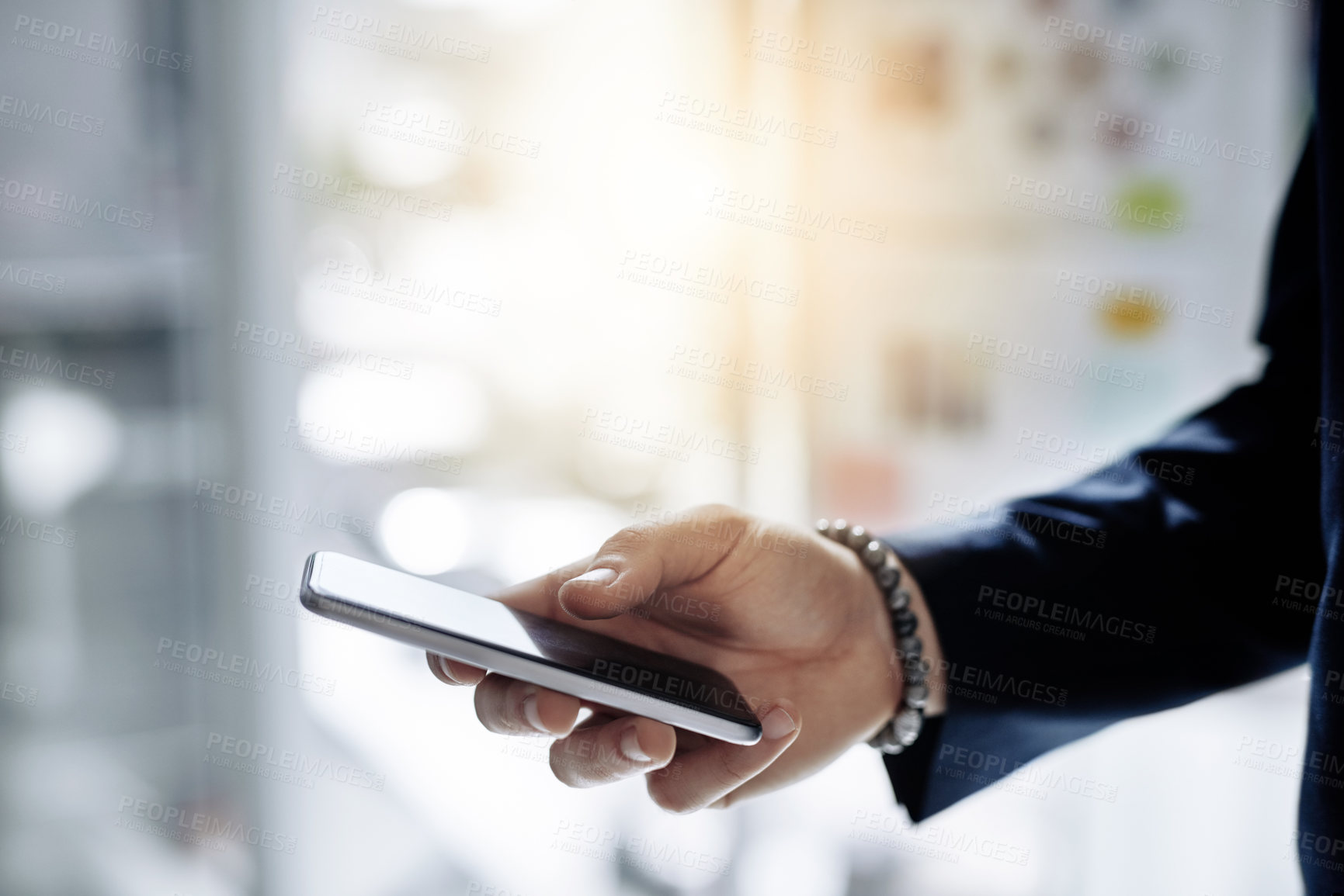 Buy stock photo Cropped shot of a businessman using a mobile phone in a modern office