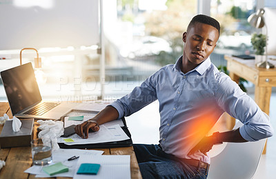 Buy stock photo Shot of a young businessman suffering from back pains while trying to work in the office