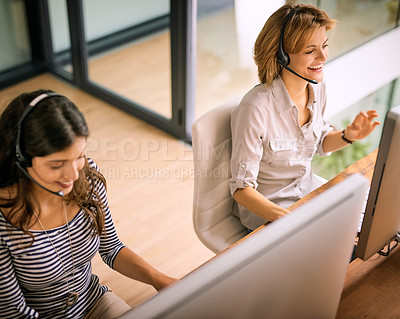 Buy stock photo High angle shot of two attractive young women working in a call center