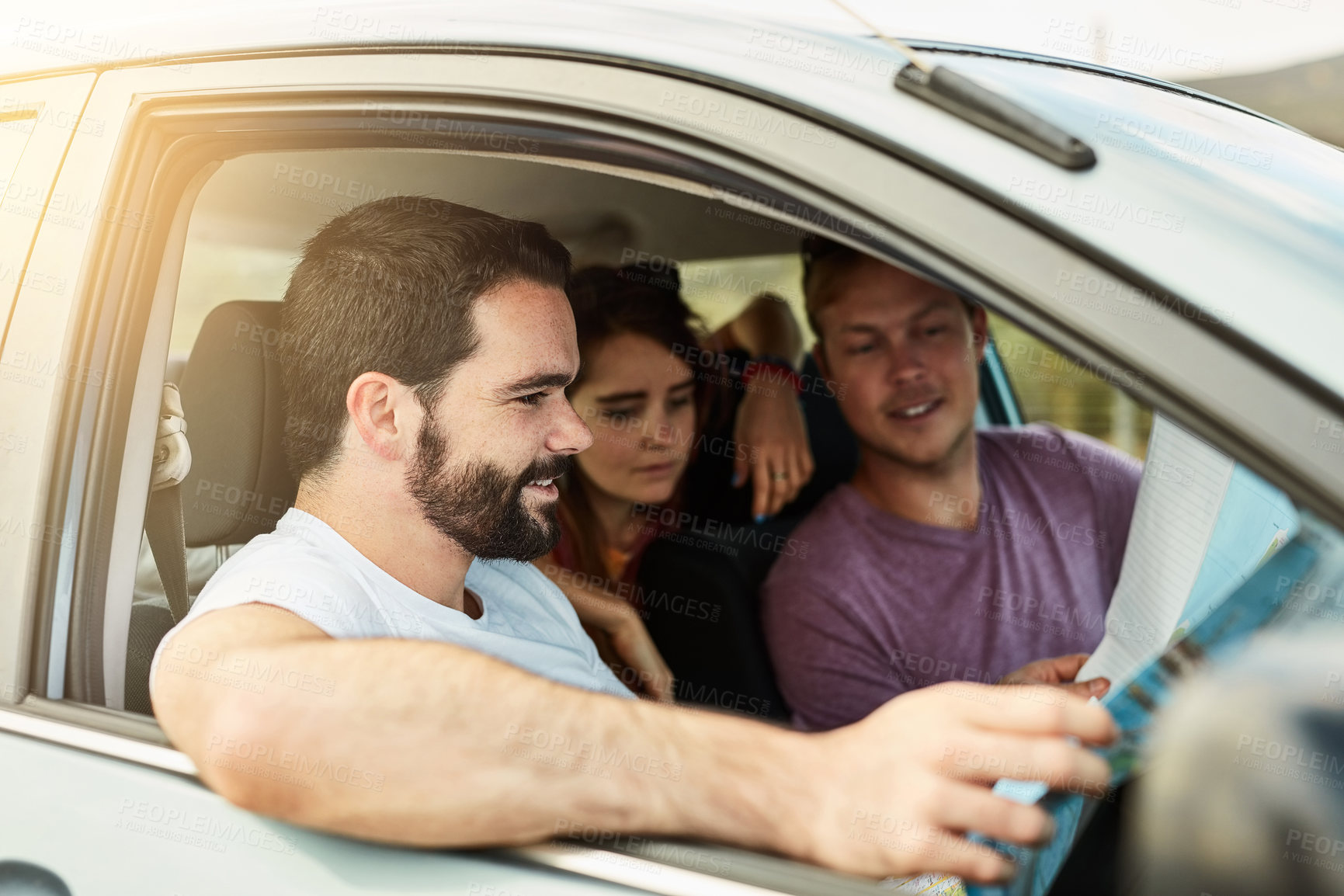 Buy stock photo Shot of a group of young friends getting ready to drive to their destination in their vehicle while looking at a map