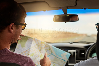 Buy stock photo Shot of two young friends reading a map while driving in their vehicle and heading to their destination