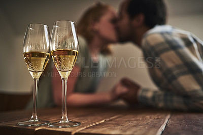 Buy stock photo Champagne, glasses and love on valentines day with a couple kissing in the background of a restaurant for romance. Alcohol, drink or dating with a man and woman sharing a kiss on a romantic date