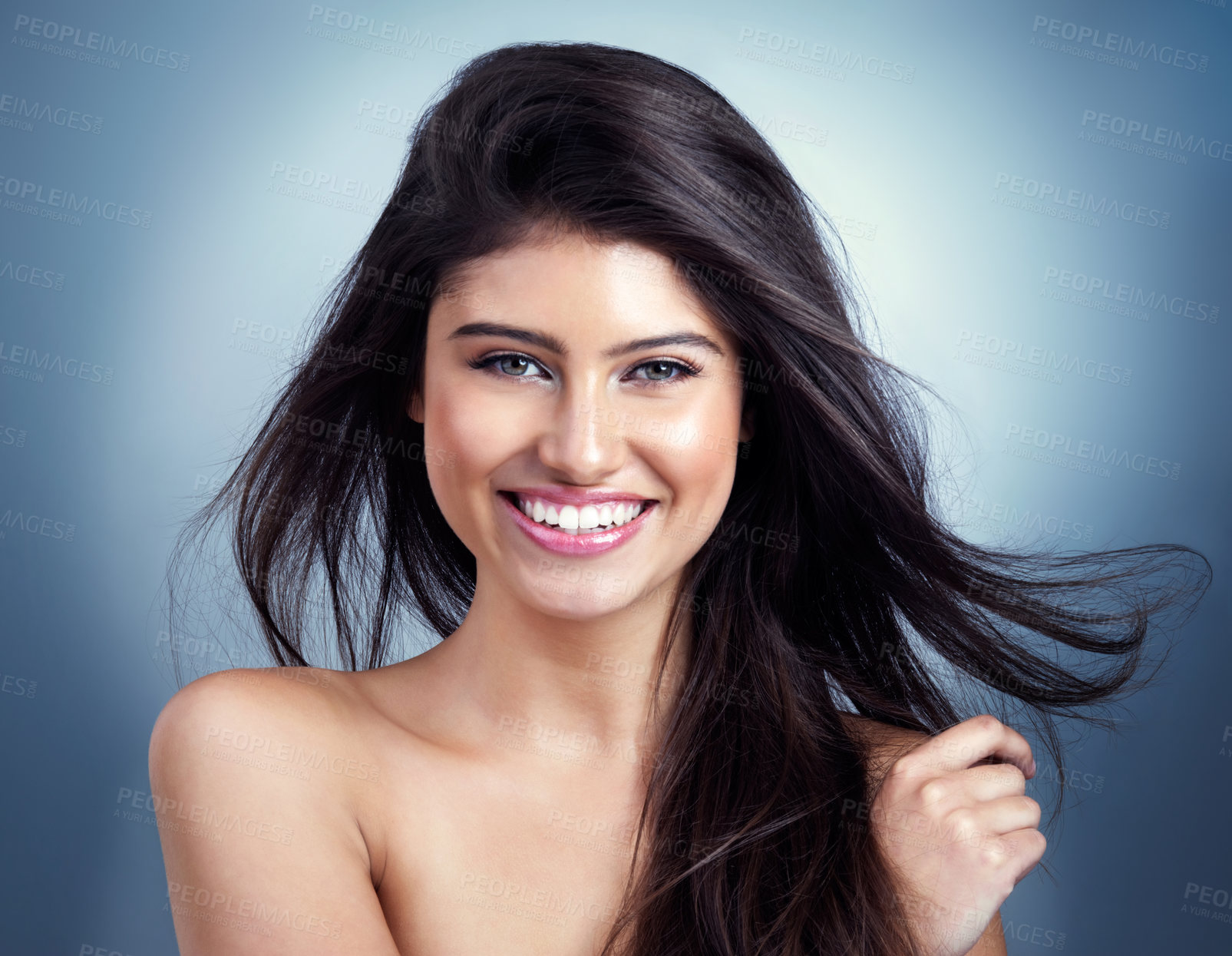 Buy stock photo Studio shot of a beautiful young woman posing against a blue background