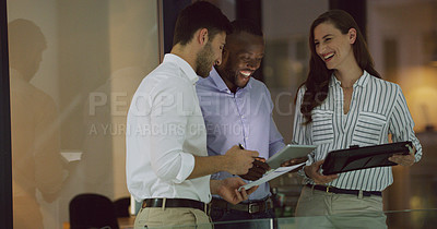 Buy stock photo Cropped shot of three businesspeople looking over a tablet while standing in the office lobby