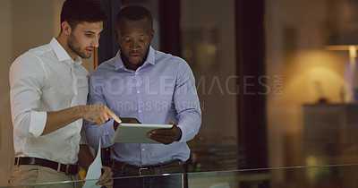 Buy stock photo Cropped shot of two businessmen looking over a tablet while standing in the office lobby
