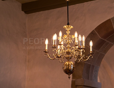 Buy stock photo Old fashioned brass chandelier with candle light bulbs hanging from roof or ceiling in a historic building and vintage room. Shiny ornamental, medieval, ancient and antique light fixture in a mansion