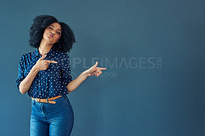 Buy stock photo Studio shot of a young woman pointing towards copy space against a gray background