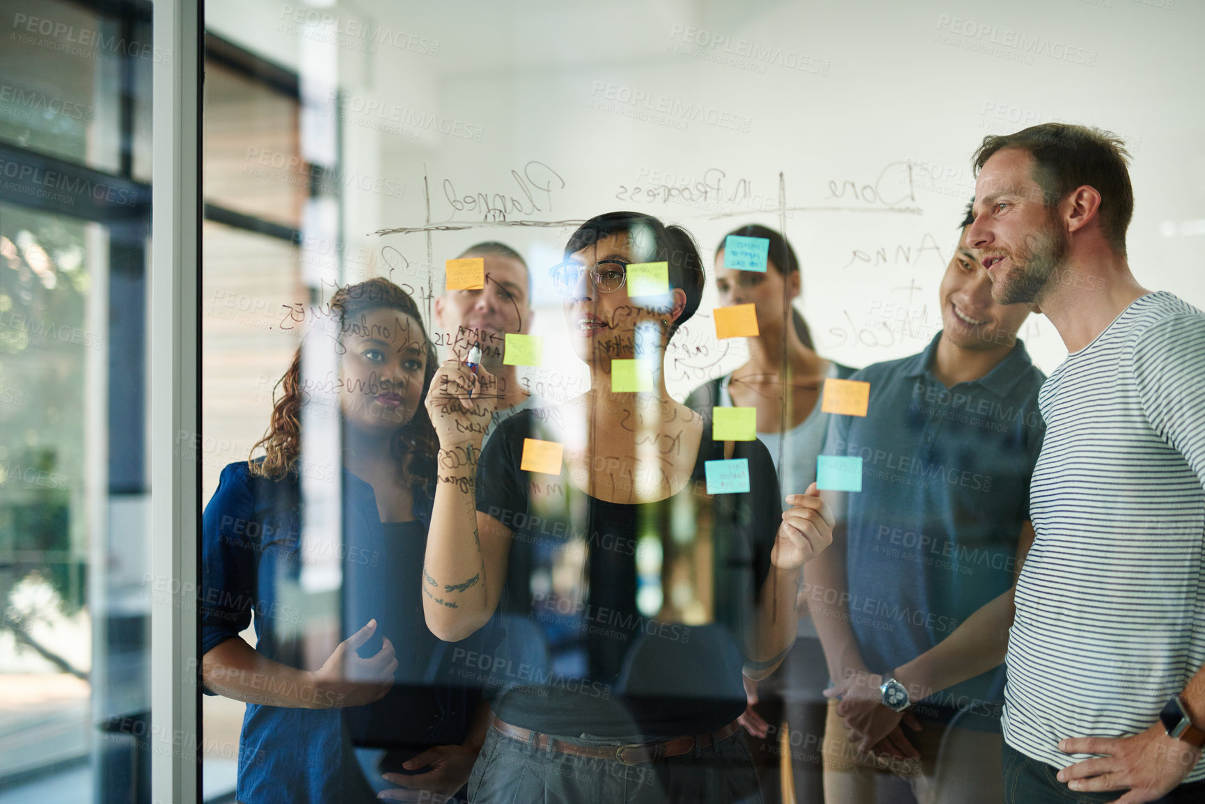 Buy stock photo Cropped shot of a group of young designers planning on a glass board