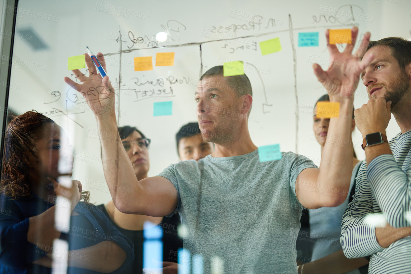 Buy stock photo Cropped shot of a group of young designers planning on a glass board