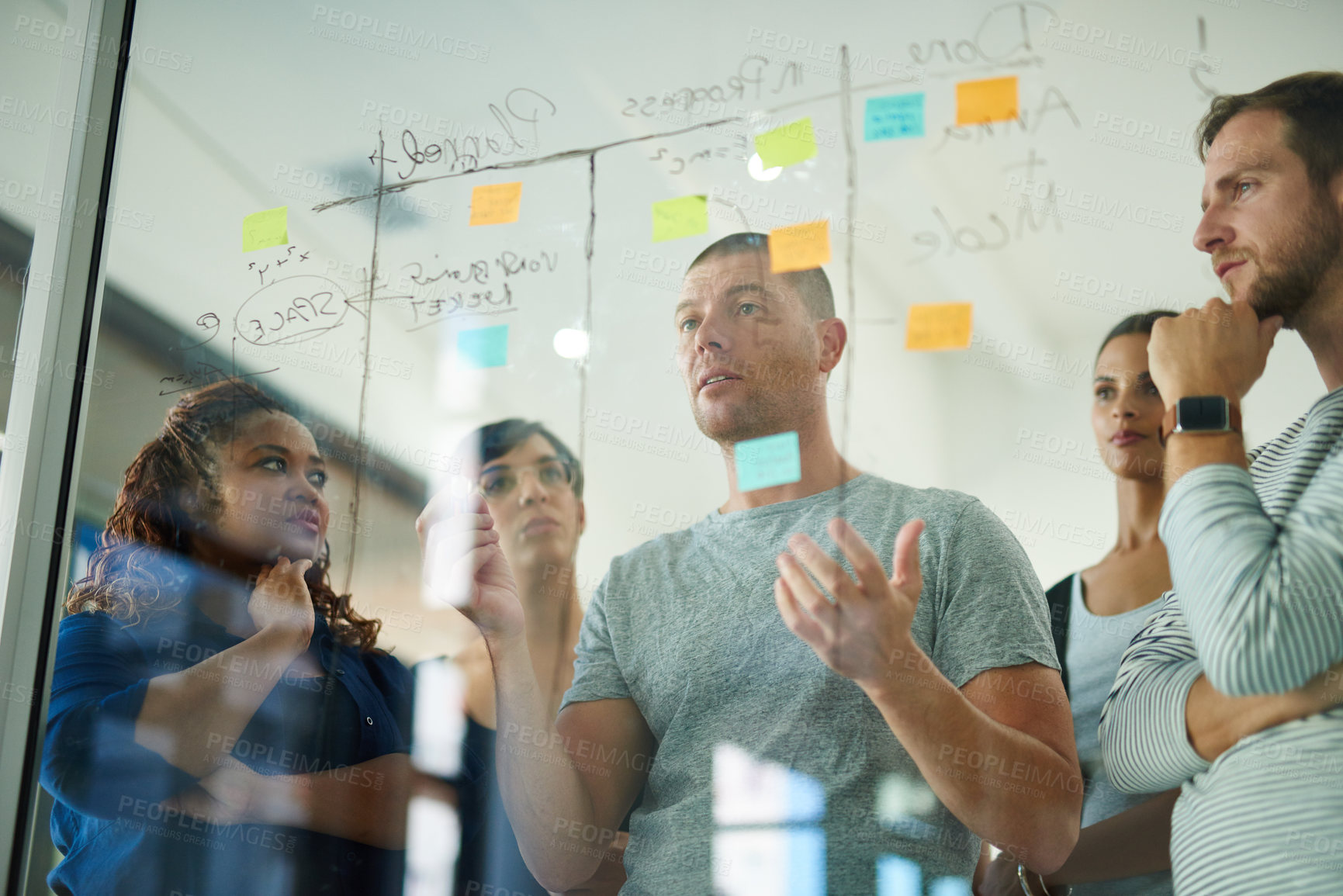 Buy stock photo Teamwork, unity and innovation at work, group of business people working together to meet a deadline. Serious  creative team planning and sharing ideas, writing on sticky notes and brainstorming 