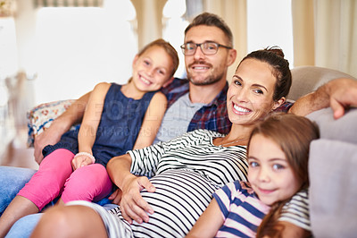 Buy stock photo Portrait of a happy young family posing on their sofa at home
