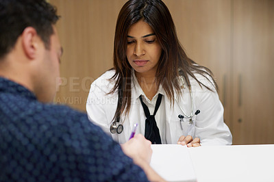 Buy stock photo Shot of doctor assisting a man filling in paperwork in a hospital