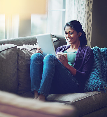 Buy stock photo Home, Indian woman and tablet on sofa to relax, rest and comfortable with technology in living room. Apartment, happy girl and digital for streaming comedy, funny film and watch movie with coffee cup