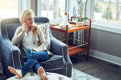 Buy stock photo Shot of a young woman relaxing on the sofa with a cup of coffee at home