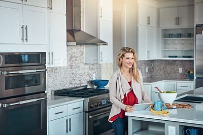 Buy stock photo Shot of a young woman using a digital tablet while baking at home