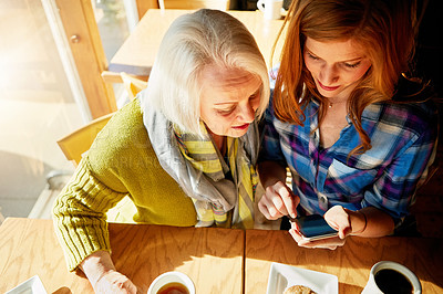 Buy stock photo Senior woman, daughter and smartphone and in cafe for social media learning, post or coffee shop. Female person, mother and drinking caffeine for morning breakfast with muffin, browsing or search