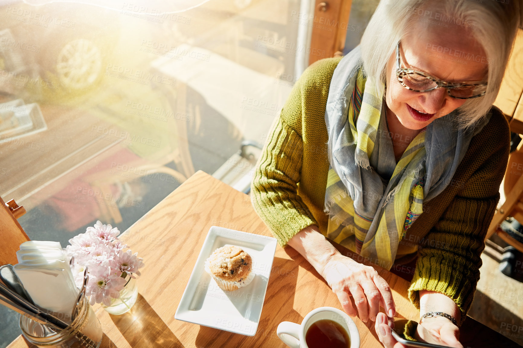 Buy stock photo Shot of a senior woman texting on her cellphone in a cafe