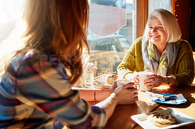 Buy stock photo Shot of a young woman and her senior mother bonding together in a cafe