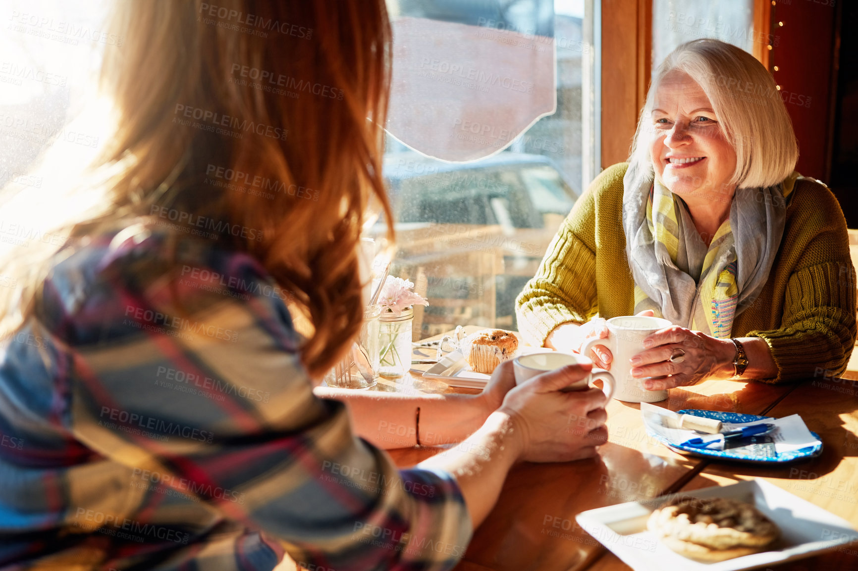 Buy stock photo Shot of a young woman and her senior mother bonding together in a cafe