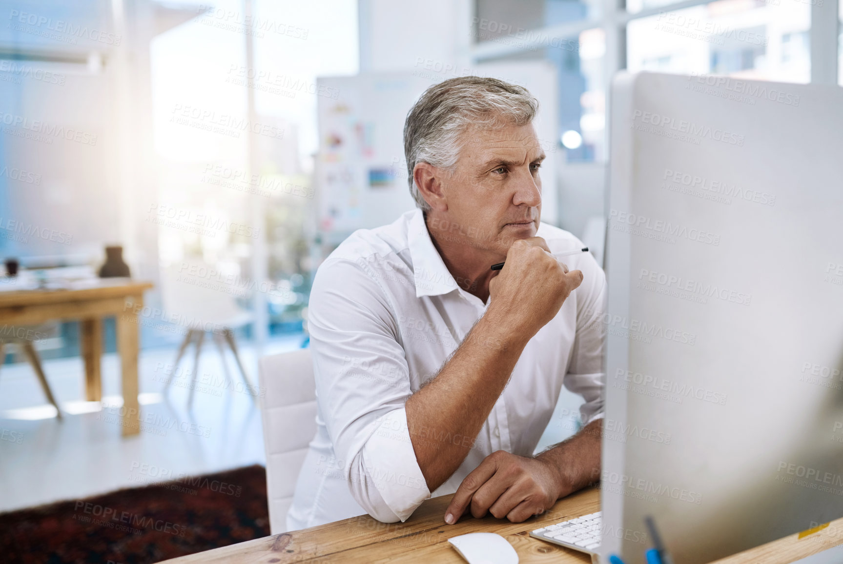 Buy stock photo Shot of a mature businessman working on his computer while sitting in the office at work