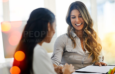 Buy stock photo Shot of two young businesswomen talking to each other while being seated in the office at work