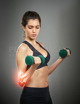 Buy stock photo Studio shot of an attractive young woman holding a dumbbell while CGI shows an injury in her elbow