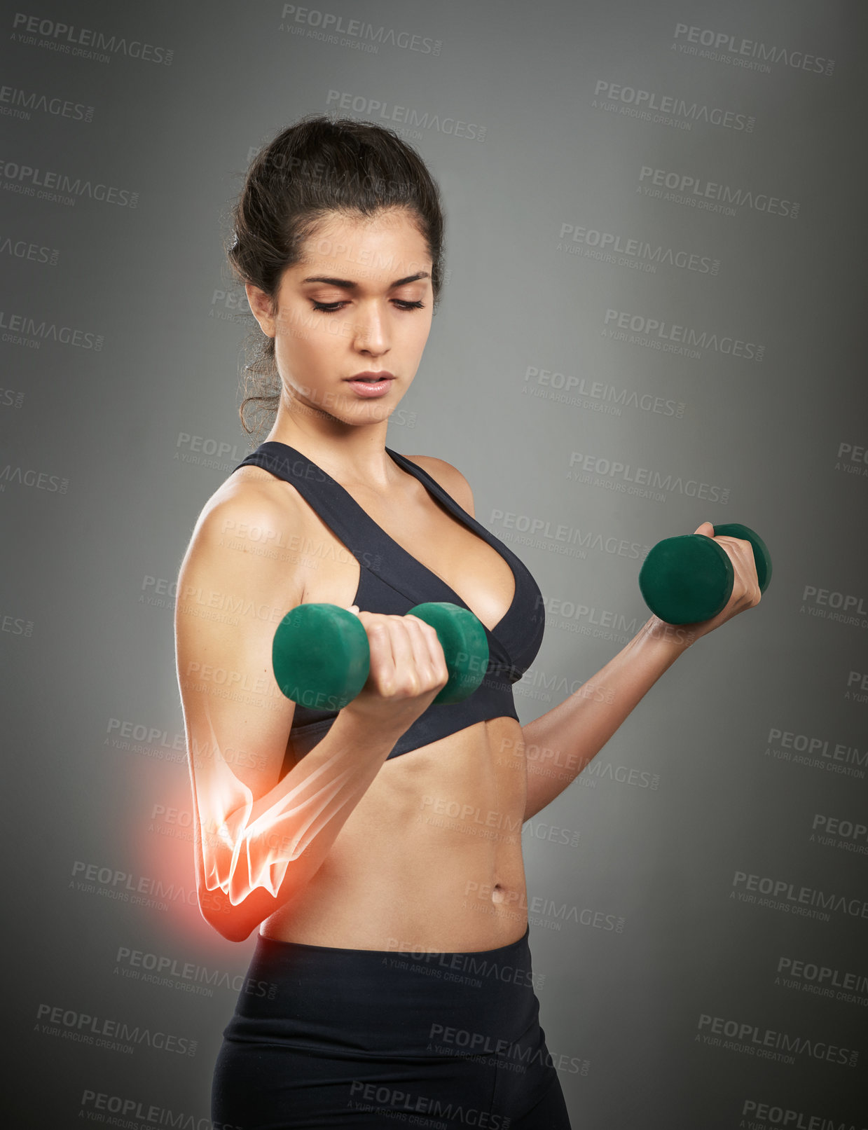 Buy stock photo Studio shot of an attractive young woman holding a dumbbell while CGI shows an injury in her elbow