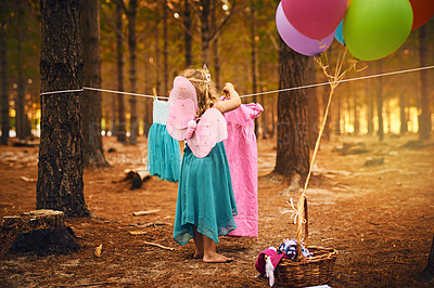 Buy stock photo Shot of an unrecognizable little girl hanging a dress up on a piece of rope while standing outside in the woods