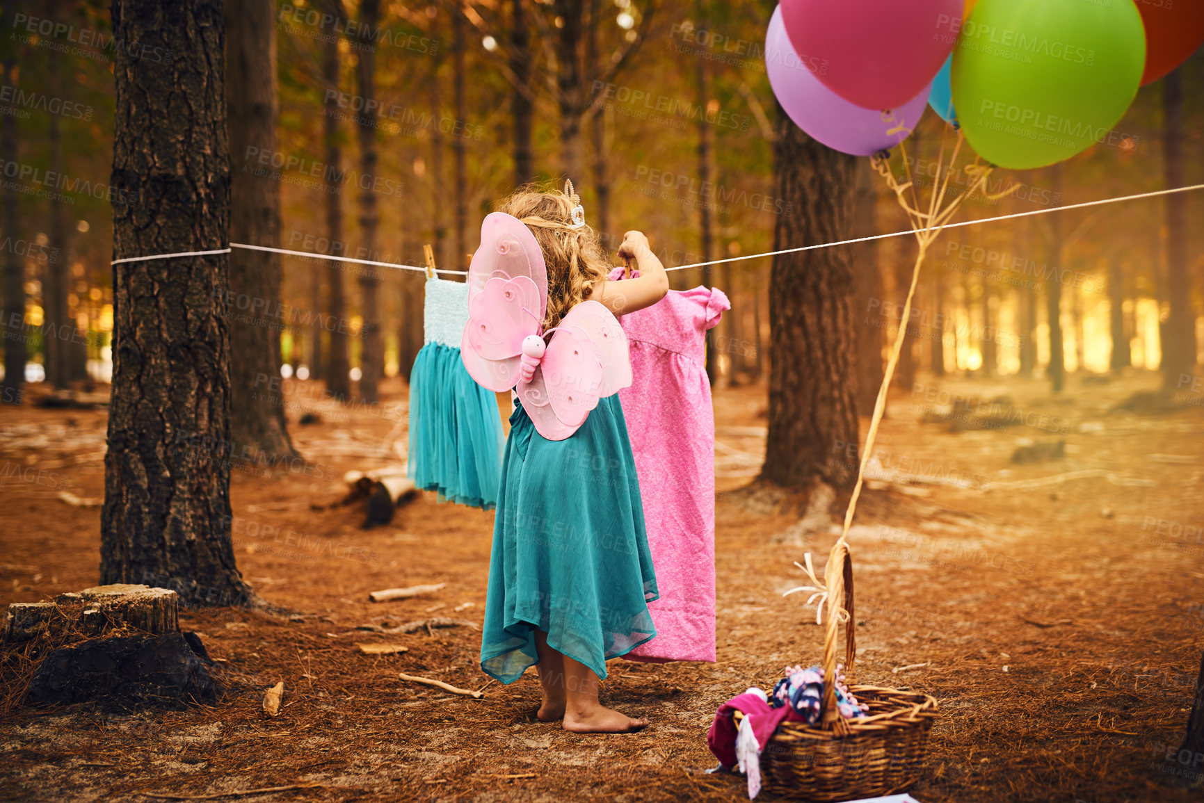 Buy stock photo Shot of an unrecognizable little girl hanging a dress up on a piece of rope while standing outside in the woods