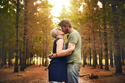 Buy stock photo Shot of a loving couple engaging in a kiss while standing outside in the woods