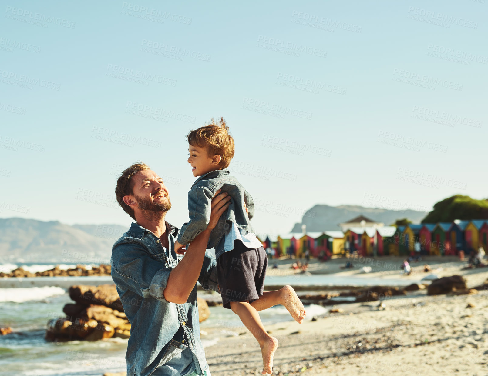 Buy stock photo Shot of a young Father tossing his son into the air at the beach