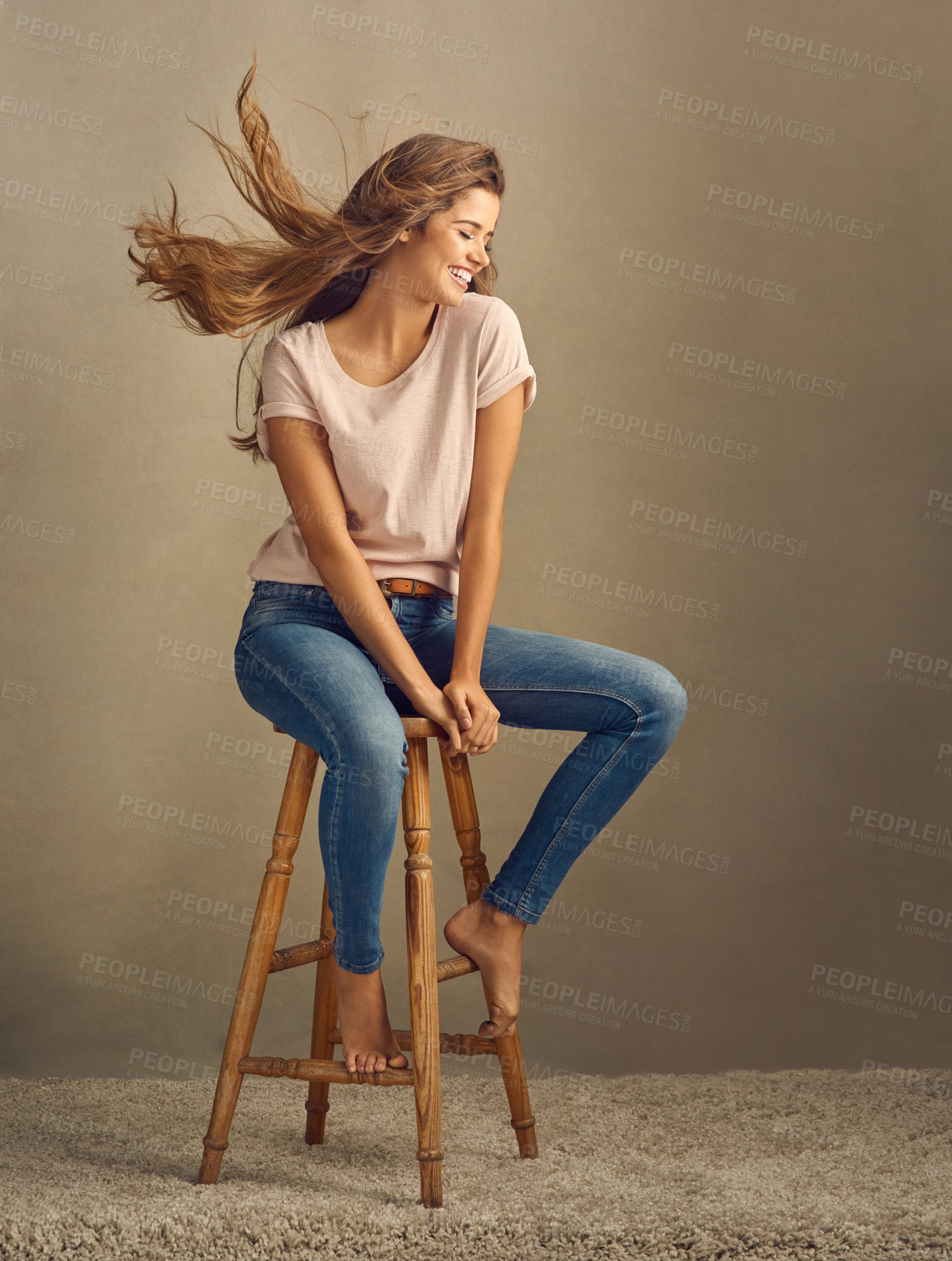 Buy stock photo Chair, smile and wind with woman in studio on brown background for casual fashion or style. Carpet, denim jeans and trendy outfit with happy model on mockup space to relax for natural wellness