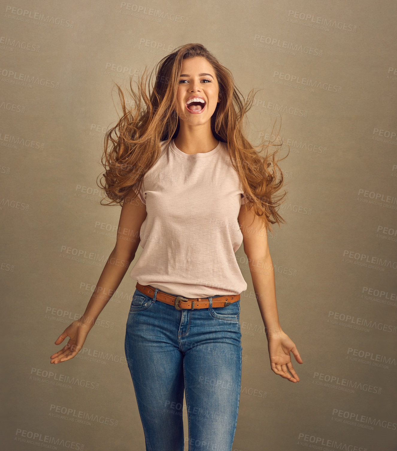 Buy stock photo Excited, woman and portrait or wind for fashion in studio or wow for style or cosmetics. Beauty, model girl and hair care or shampoo, treatment and jump or jeans for trendy outfit by brown background