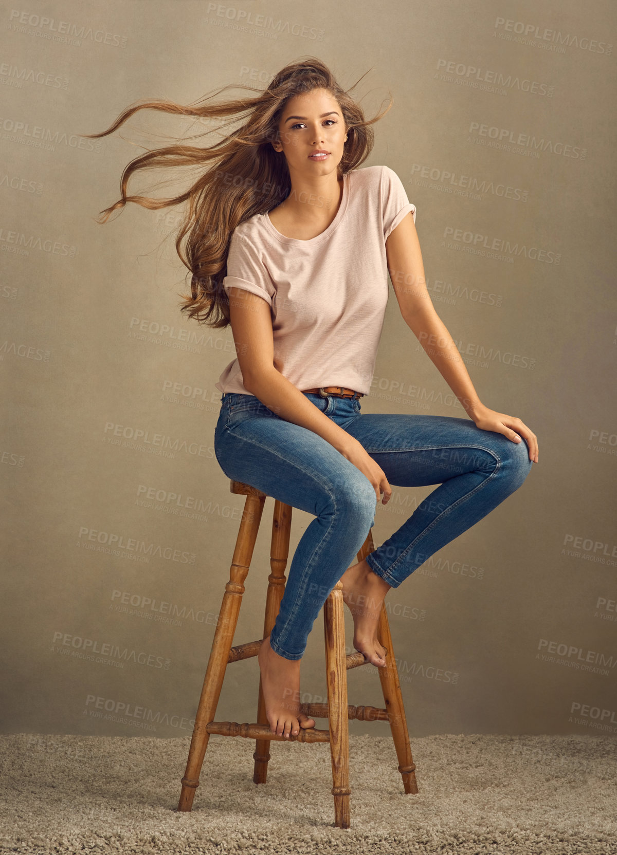 Buy stock photo Portrait, woman and wind or fashion in studio with hair care and calm for style or cosmetics. Beauty, model girl and confidence for shampoo, aesthetic and denim or relax on chair by brown background