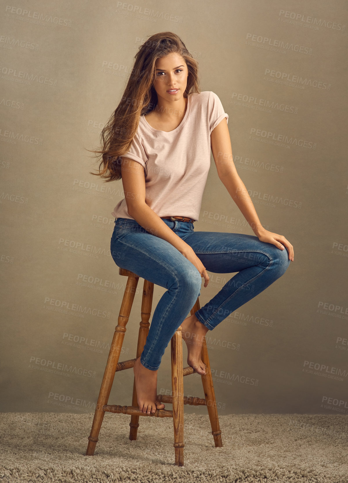 Buy stock photo Woman, portrait and serious on chair for beauty on studio background with confidence, barefoot and style. Female person, aesthetic and model with long hair, denim and jeans for cool, calm or elegant