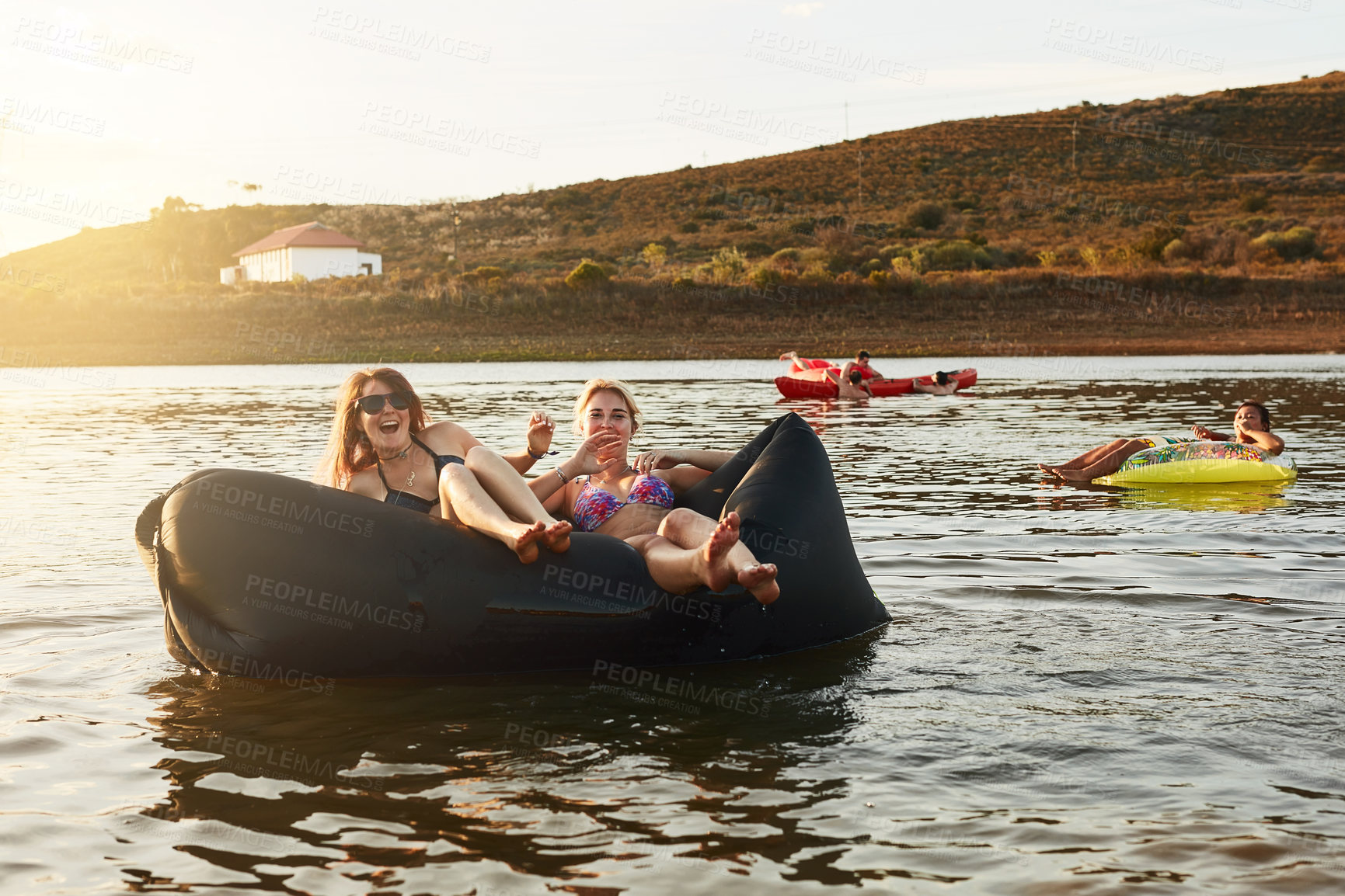 Buy stock photo Portrait, float and friends in lake on holiday to chill, smile or enjoy summer break or vacation together. Happy, laughing or women on floater to relax in water for fun memory or bonding on weekend