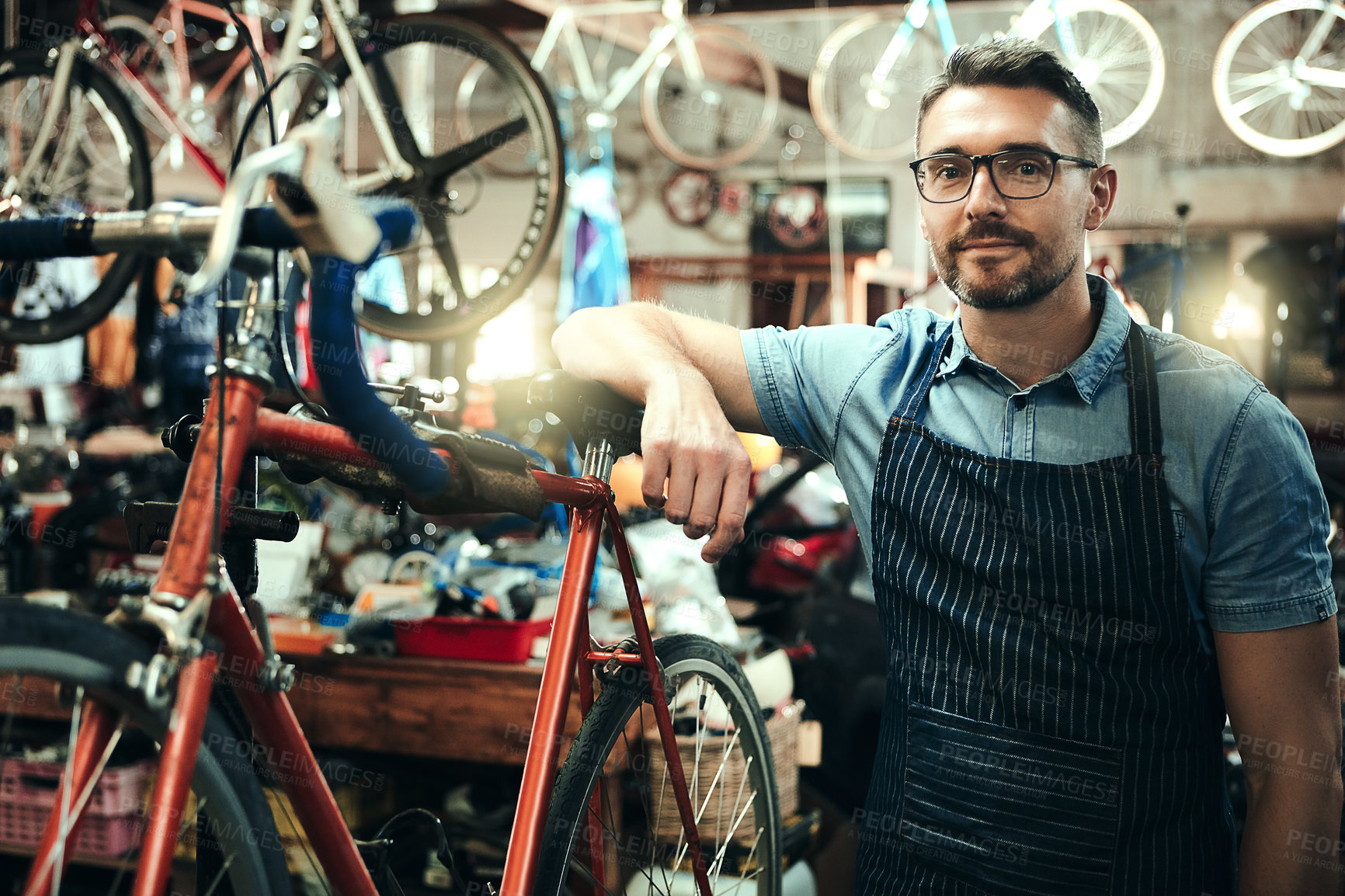 Buy stock photo Bicycle, garage and repair shop for man, portrait and small business of mechanic, apron and equipment. Proud, owner and person with service, maintenance and tools for bike, technician and working