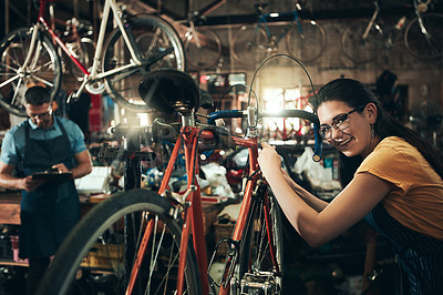 Buy stock photo Happy woman, portrait and bicycle mechanic with inspection, fix or maintenance at repair shop. Young female person, cycling technician or engineer working on bike with tools or equipment at workshop
